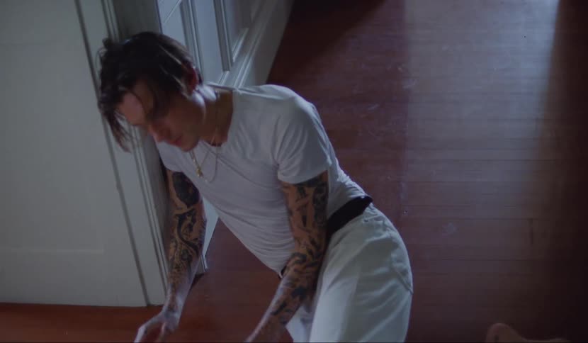 A male teenager runs and stumbles down a hallway and then falls to the floor
