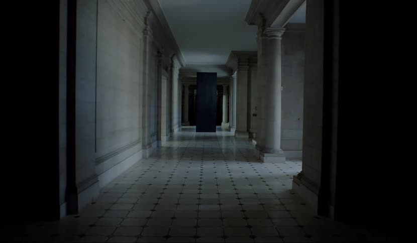 A white hallway with a black pillar
