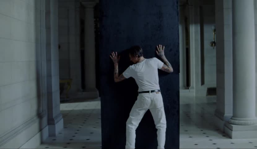 A teenager touches a wall and then throws his body against it and falls to his knees