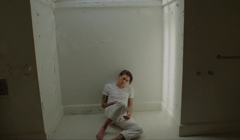 A man sitting on the tile bathroom floor leaning against the wall nodding off as if high