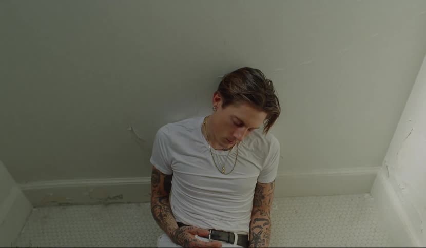 A man sitting on the floor banging his head against the wall