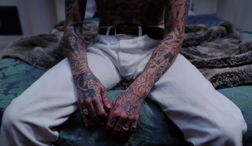 Man with tattoos sit on bed in the bedroom