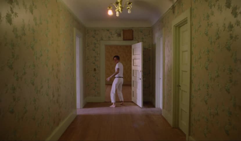 A man stumbling down a long hallway in a house