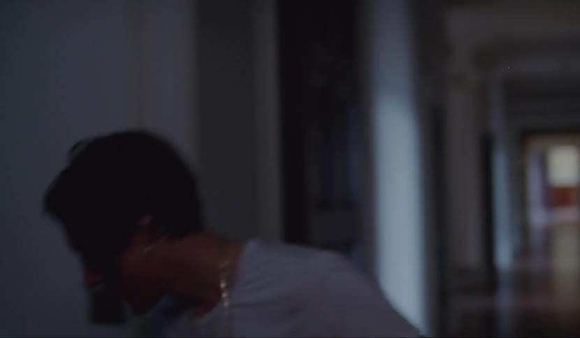 A distressed man stumbling up a spiral staircase in a dimly lit hallway