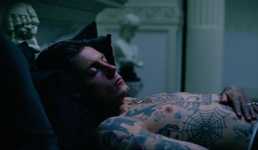 A tattooed man sleeping in a bed becoming covered in shadow