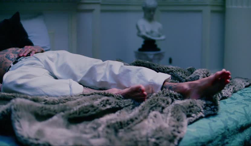 Man lies in bed on furry bedspread twitching