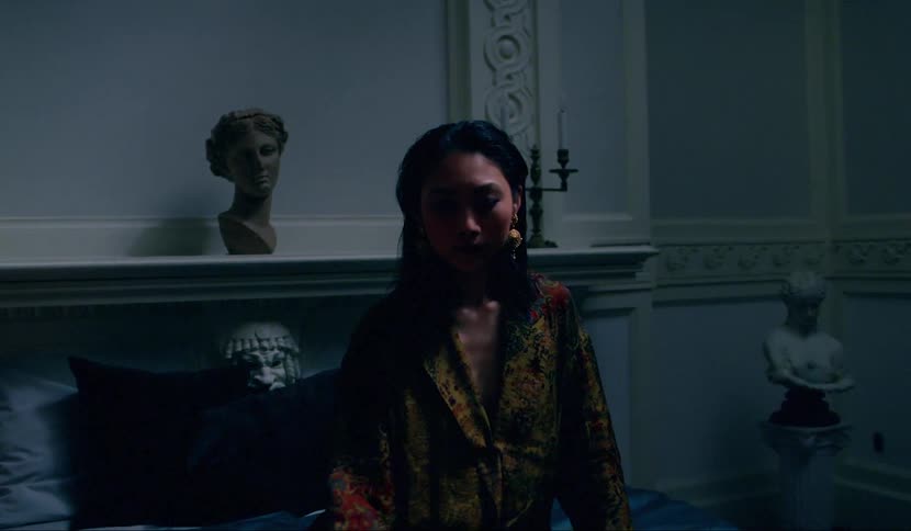 A woman is sitting on a bed and a man is sitting on the floor in a house