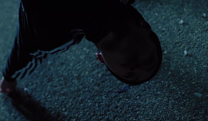 A man is suspended bent backwards with arm and hand dragging on the ground and his head above it
