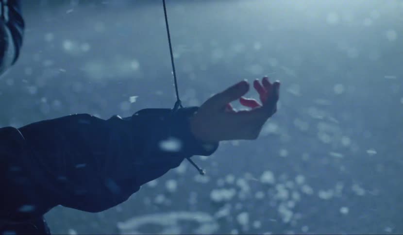 Person tangled and hanging upside down reaches out as particles across the pavement