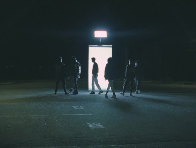 A group of dancers stands in front of the door and goes in different directions at night