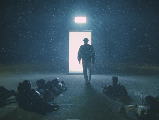 A group of dancers lying dead on the ground resurrect and walk through doorway where the light comes from at night