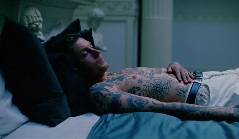 Shirtless tattooed man laying in bed