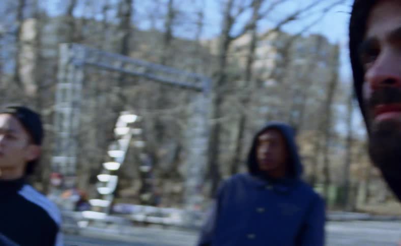 A group of dancers look at a specific point in the woods