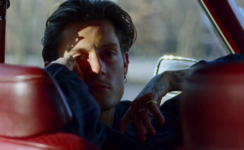 Man with tattoo sitting in the car looks ahead in the car