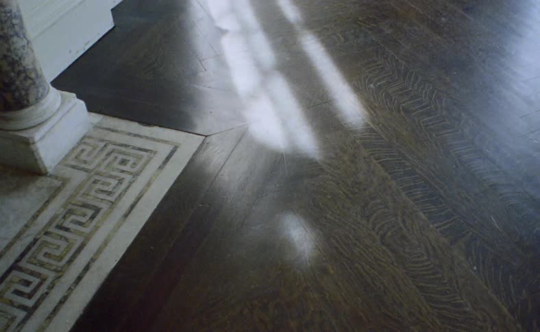 A wooden floor with the sunlight reflecting off of it