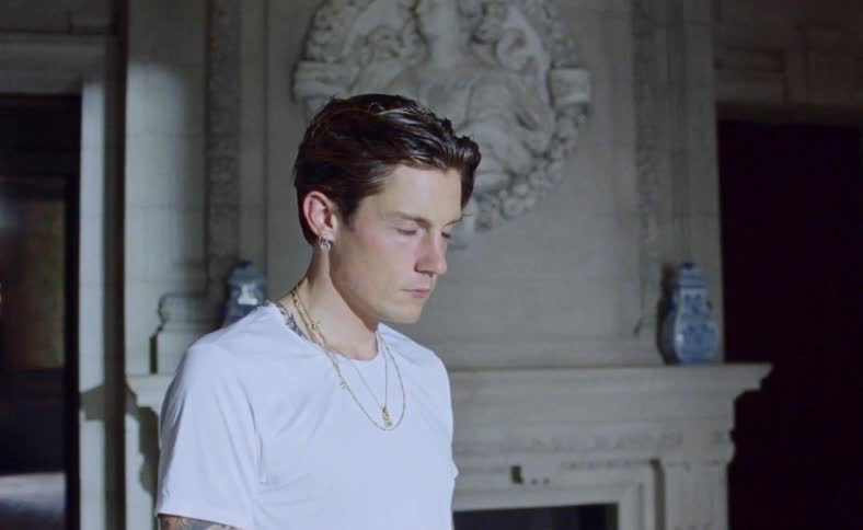 Young man standing in front of fireplace inside mansion