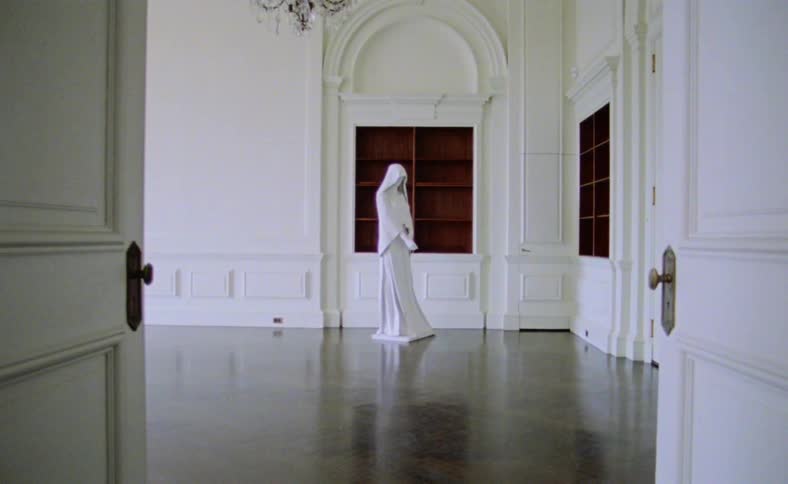 Life size white statue stands in ornate empty room