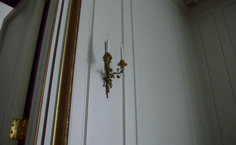 An ornate candle stick light fixture hangs on the wall
