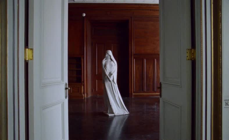 A white marble statue stands in an empty room with wooden built ins