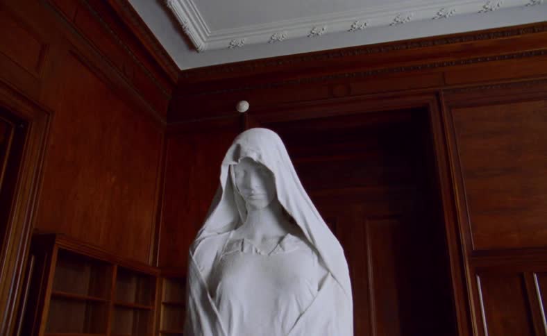 White statue stands out against hardwood furnishing and paneling