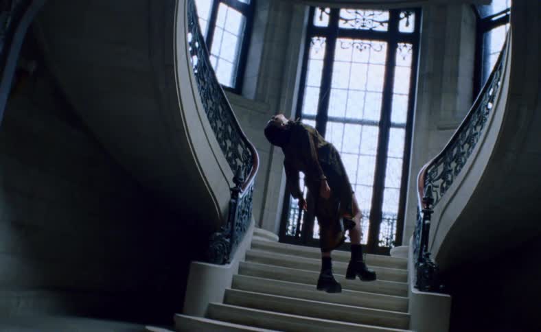 A woman hanging from the ceiling at the bottom of a staircase