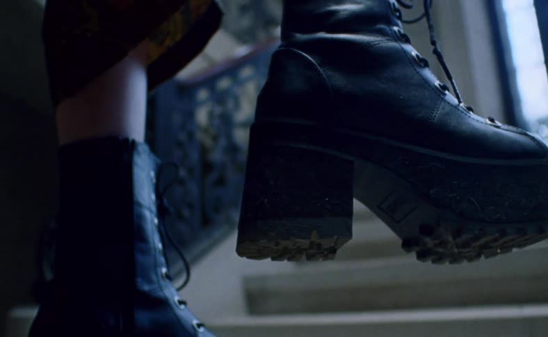 A womans boots and legs hanging at the bottom of a staircase