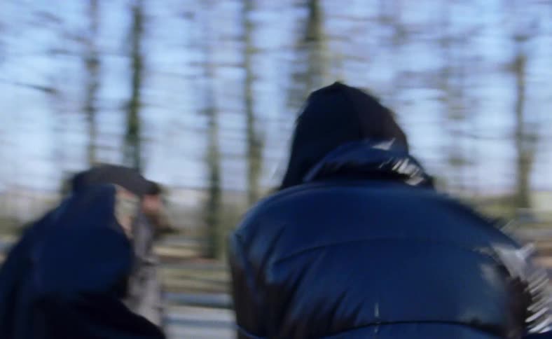Men twitch and dance on street outdoors surrounded by leafless trees
