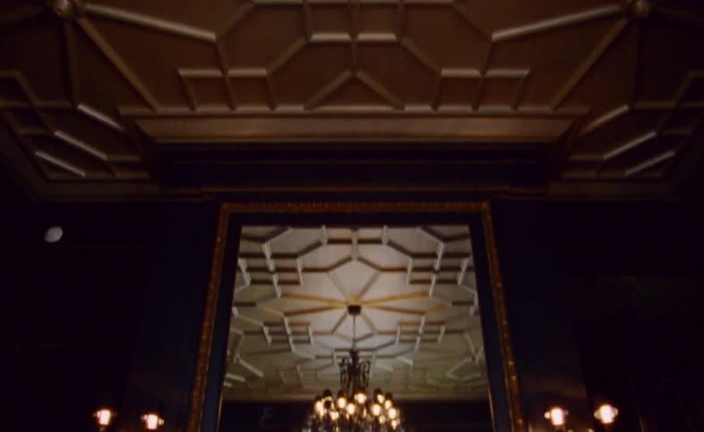 Chandelier hangs from the ceiling of a room with the mirror above the fireplace