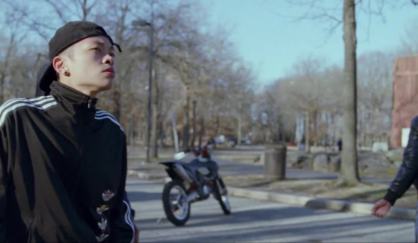 A group of men stand outside looking off in to the distance and then start street dancing