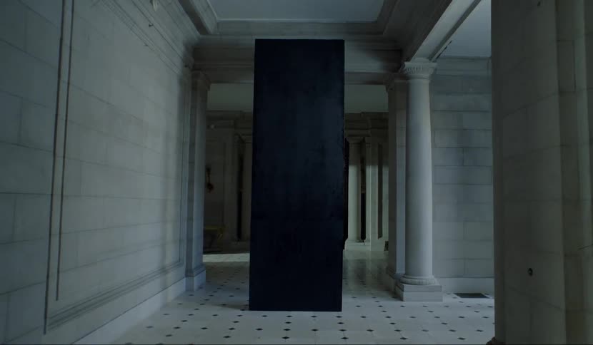 A white hallway with a black column in the middle of it