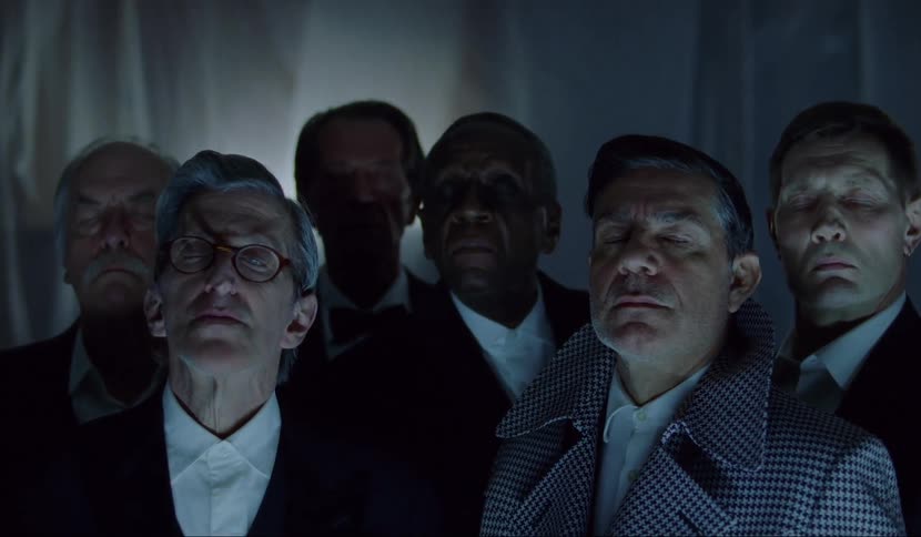 Six men stand close together with their eyes closed