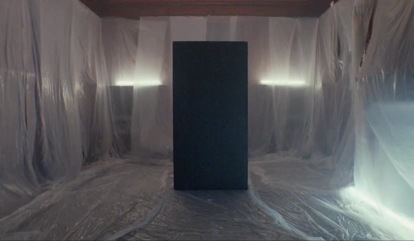 A black monolith in a plastic covered room