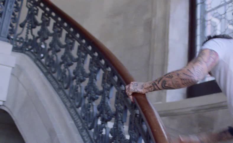 Film footage of a young man struggling to get up a staircase