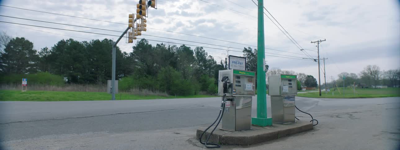 Two gas pumps sit near a street as a truck drives by