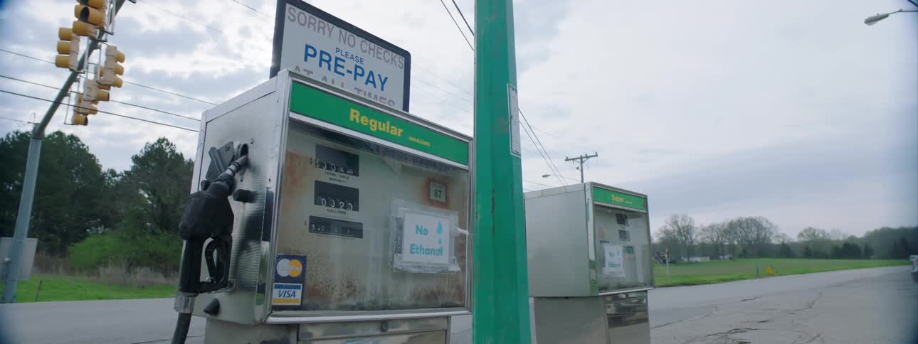 Close up of vintage fuel pumps as cars drive by in background in a small town