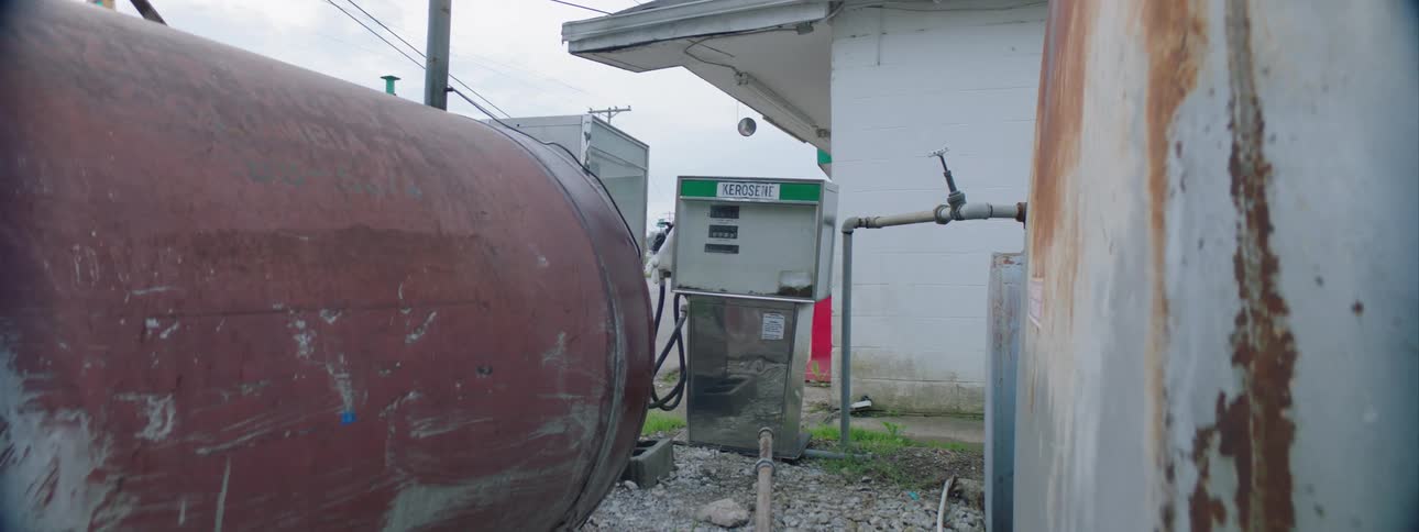 The exterior of a small gas station contains old and rusted equipment