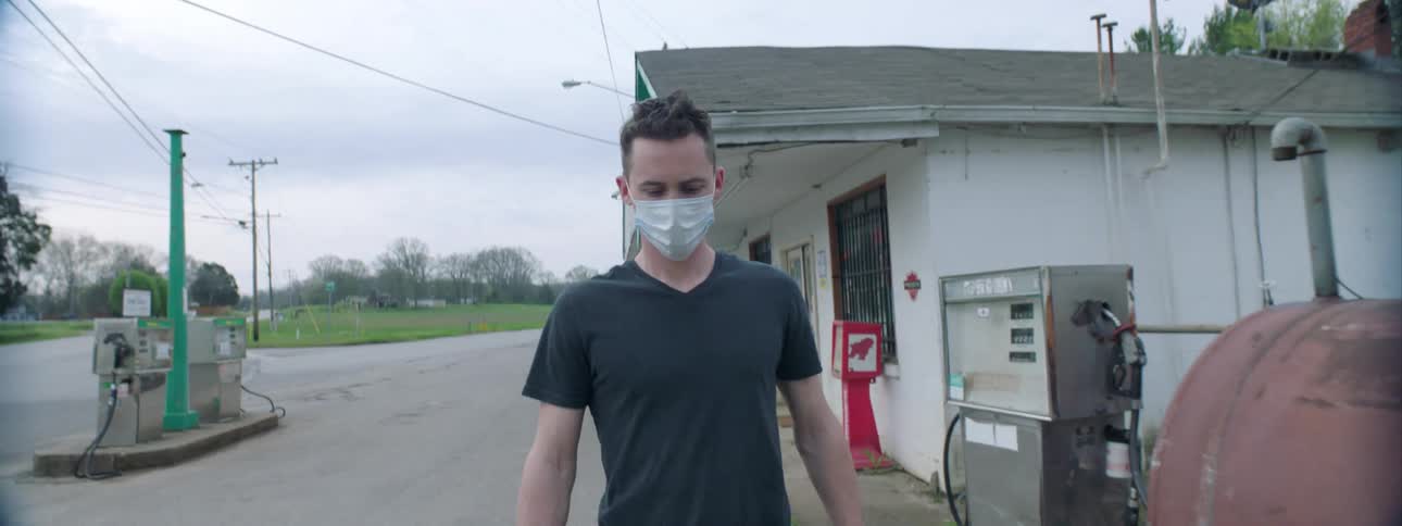 Man wearing a mask because of the coronavirus gets out of the gas station