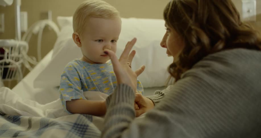 A woman playing with a baby in a hospital bed