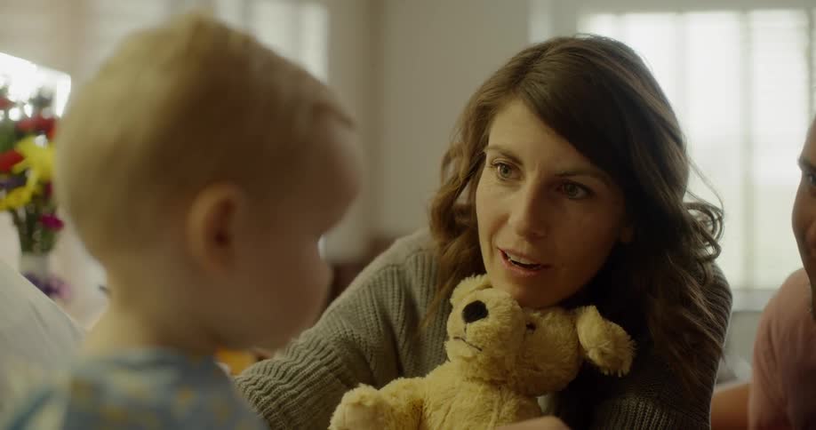 Parents talk with their baby and show a teddy bear
