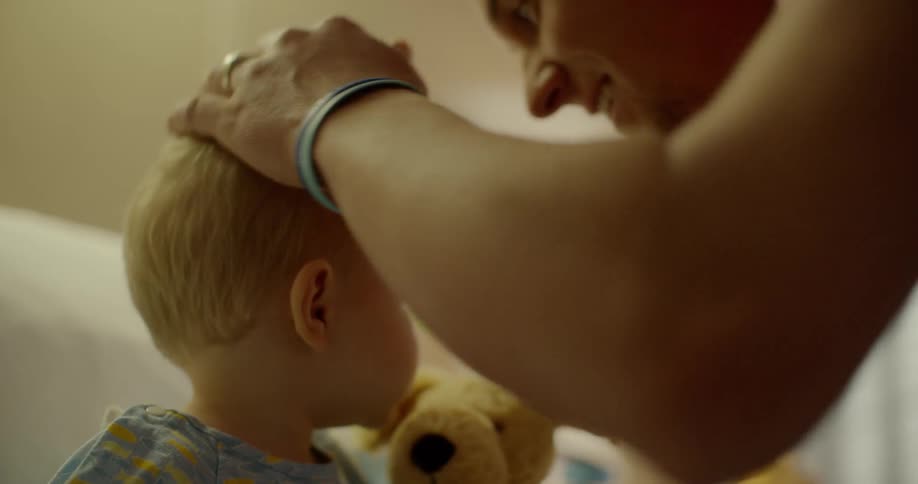 A dad bends down and kisses his child who is in a hospital bed