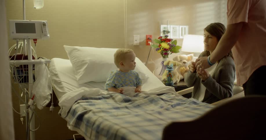 A woman and a man look after a child in a hospital bed