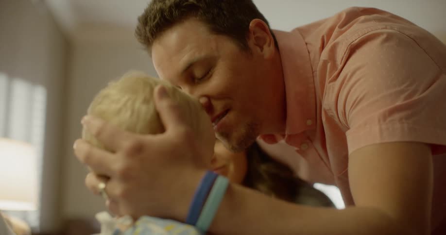A mother and father kiss their child who is in a hospital bed