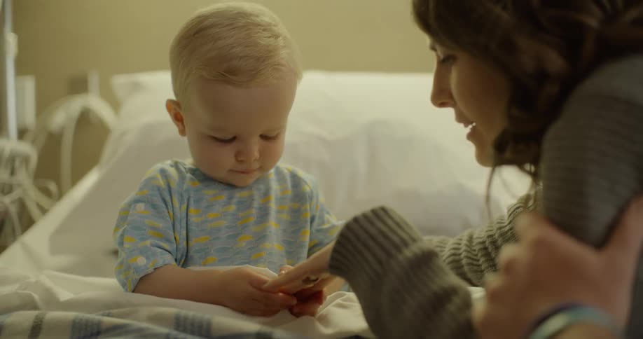 A woman talks to a child in a hospital bed