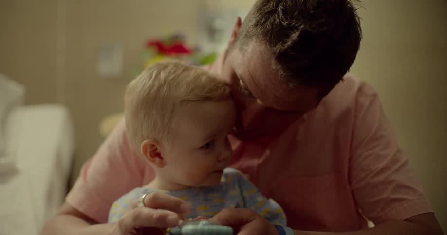 A man holds his son and shows him a toy
