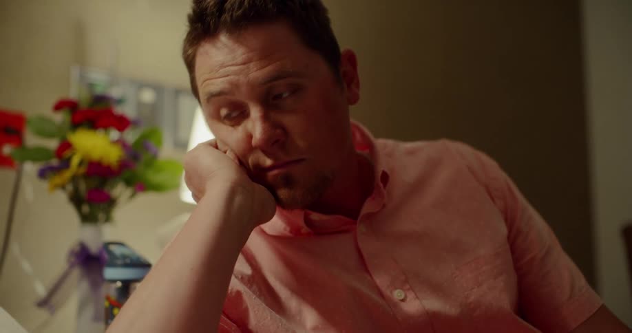 A man sits and looks on with his chin rested in his hand