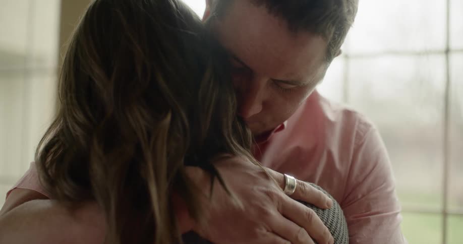 A husband hugs his wife
