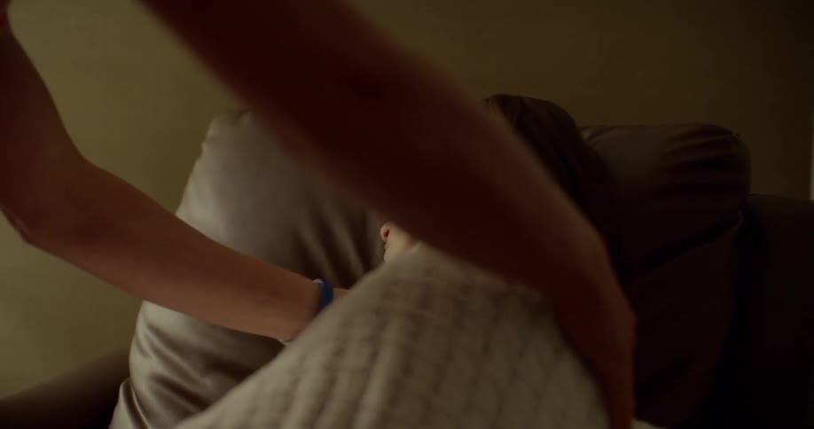 A husband covers his wife with a blanket as she sleeps in a chair