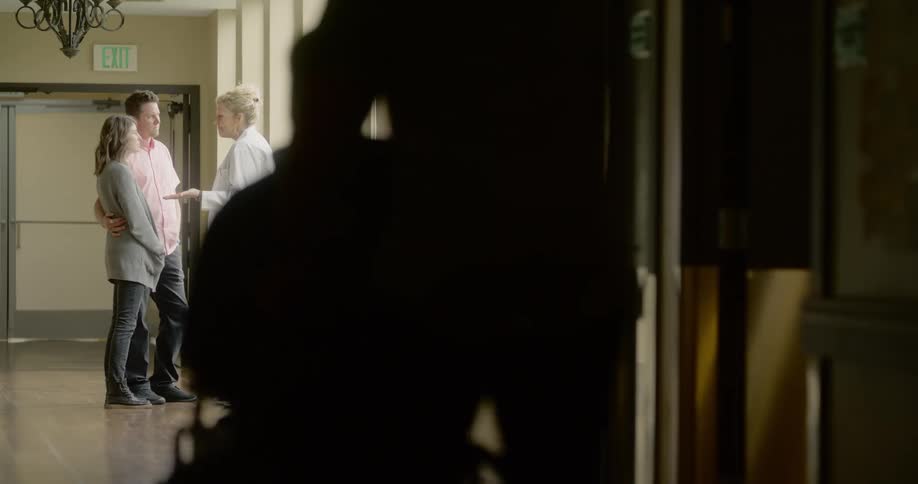 Blonde female doctor speaks to man and woman in the hospital hallway