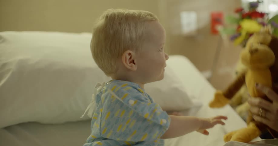Mother plays with child and stuffed toy in hospital room