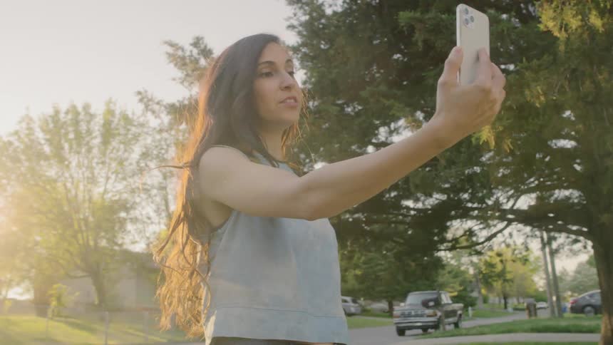 A woman is holding a smart phone and standing outdoors